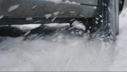 Car in the snow. Tires slide on a snowy road. Snow is flying up from the spinning wheel of a vehicle