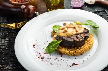 Beef steak with bulgur and mushrooms on a plate. Restaurant menu. European cuisine.
