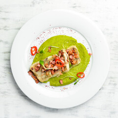 Baked hake fillet and bacon with spinach garnish on a white plate. Top view.