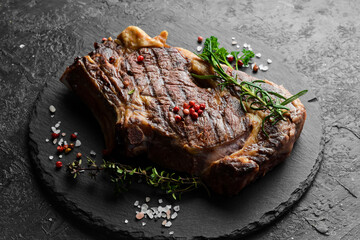 Juicy grilled steak on the bone cooked on the grill. Barbecue. On a black stone background.