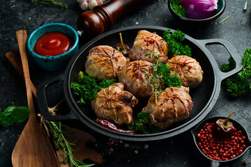 Grilled Juicy Turkey Cutlets. In a pan with spices and herbs. On a black stone background. Top view.