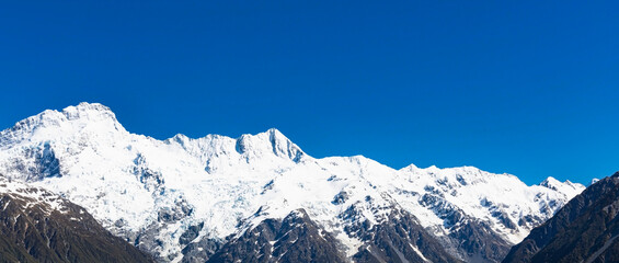 The mountain view of alpine as snow-capped mount peaks in  Swiss Mountain alps against the blue sky background