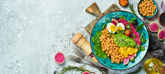 Fototapeta na wymiar Buddha bowl: chickpeas, avocado, egg, watermelon radish and spinach. Delicious balanced nutrition concept on stone background.
