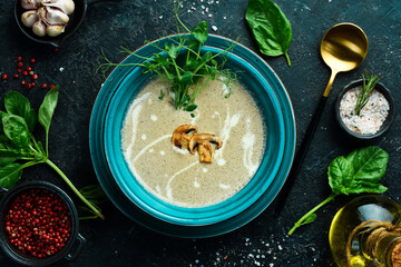 Mushroom cream soup with cream and conjut. In a blue plate. On a black stone background.