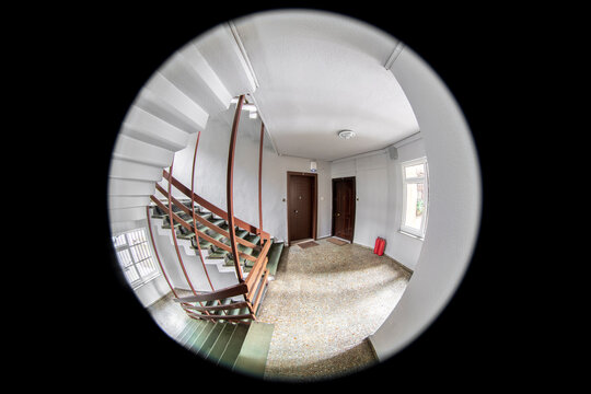 Empty corridor, floor, stairways and two neighboring doors are visible through the door peephole       