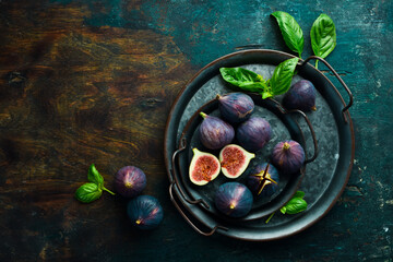 Figs and leaves on a dark stone table. On a dark background. Space for text. Top view.