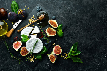 Obraz na płótnie Canvas Cheese plate. Brie cheese, fresh figs and honey on stone board. Space for text. Top view.