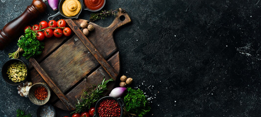 Stone black cooking background. Kitchen board with vegetables and spices. On a black stone background. Top view.