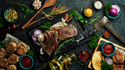 Barbecue. Grilled striploin steak with spices and rosemary. On a black concrete background. Free space for text.