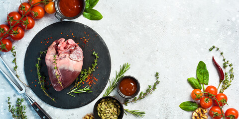 Raw pork heart on a black stone plate with spices and herbs. Meat. On a stone background. © Yaruniv-Studio