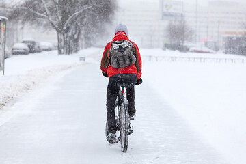 A man rides a bike on a winter path, rear view