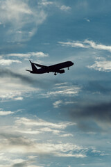 Silhouette of airplane in the sky at sunset with dramatic clouds