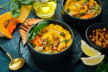 Hummus from chickpeas and pumpkin, with olive oil and spices. Healthy vegetarian food. On a black background.