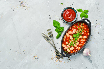 Baked beans in tomato sauce on a black stone plate. Top view. On a stone background.