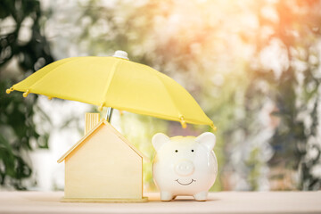 The yellow umbrella protect the home and piggy bank put on the wood in the public park, Loan or...