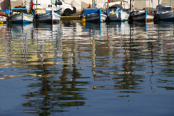 Reflections of fishing boats in the wharf. 
