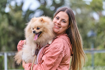 Portrait of a girl posing with her pomeranian dog in a park.