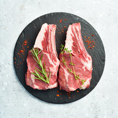 Raw veal steak on the bone, on a black slate plate. On a stone background.
