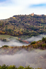 Fototapeta premium Morning mist under Mondaino, Emilia Romagna region, seen from Belvedere Fogliense between Pesaro and Urbino in the Marche region of Italy