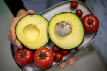 Waiter cafe restaurant cooker female hands holding fresh farm avocado and tomatoes on metallic tray