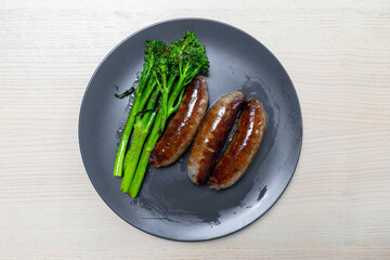 Plate of grilled sausages and broccolini.