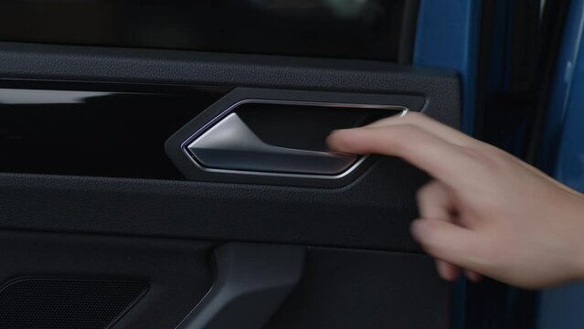 Close-up pulling the door handle from the interior of a car.