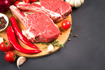 Cowboy steak recipe. Raw ribeye beef steak ready for grilling with seasonings and chili pepper on...