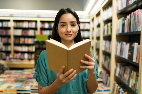 Beautiful hispanic woman buying a new book at the bookstore