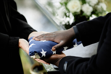 Close up of general handing folded American flag to woman at funeral ceremony for army veteran