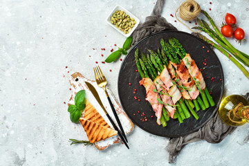 Grilled asparagus with bacon and basil on a plate. On a stone background. Top view. - obrazy, fototapety, plakaty