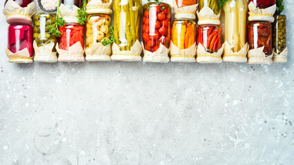 Jars with various pickled vegetables on a stone background. On a stone background. Top view.