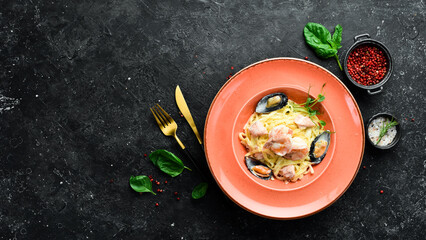 Seafood. Pasta with shrimp, mussels, cheese and basil in a plate. Italian dish. On a black stone background.