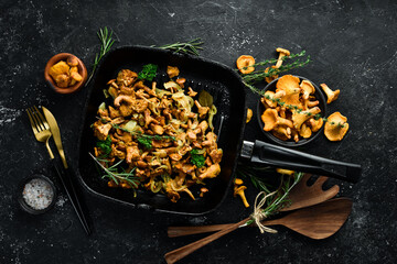 Chanterelle mushrooms fried with onions and spices in a pan on the kitchen table. Top view. Free space for text.