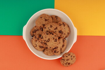  galleta de chispas de chocolate  sobre un plato en fondo de varios colores 