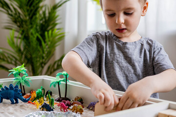 Focused baby boy confidently playing early development game kinetic sand Montessori material