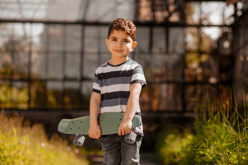 Cute asian boy in striped shirt with a skateboard