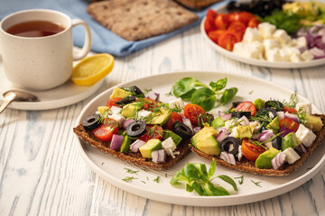 Tasty and healthy avocado, olives, cherry tomatoes and feta cheese sandwiches. Toasts  with avocado, tomatoes and feta cheese.