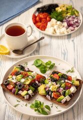 Tasty and healthy avocado, olives, cherry tomatoes and feta cheese sandwiches. Toasts  with avocado, tomatoes and feta cheese.