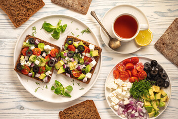 Tasty and healthy avocado, olives, cherry tomatoes and feta cheese sandwiches. Toasts  with...