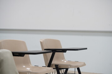 The chairs are arranged in rows for empty classes at university or school with chairs and side tables.