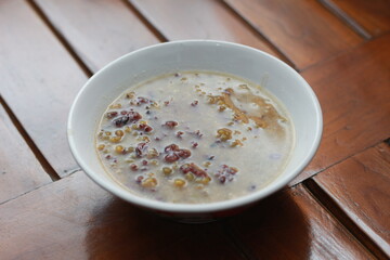 a close up of a bowl of green bean porridge and black sticky rice doused in coconut milk