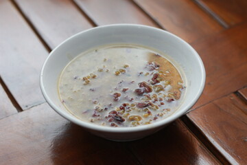 a close up of a bowl of green bean porridge and black sticky rice doused in coconut milk