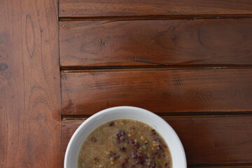 a close up of a bowl of green bean porridge and black sticky rice doused in coconut milk