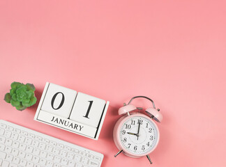  flat lay of computer keyboard, wooden calendar 01 January, pink vintage alarm clock 9 o'clock and...