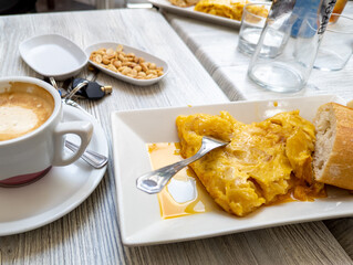 Tasty juicy potato omelette with coffee and peeled peanuts, typical Spanish tapa
