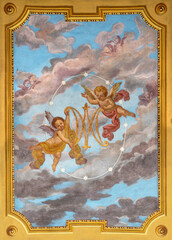 IVREA, ITALY - JULY 15, 2022: The ceiling fresco of angels with the marianic initials in the church Chiesa di San Salvatore by G. Silvestro (1914).