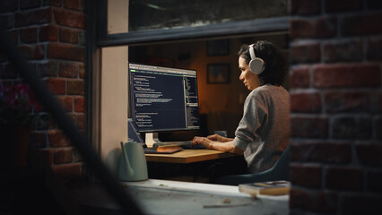 Hispanic Female Programmer in Headphones Listening Podcast and Working on Desktop Computer, Screen Shows Coding Language User Interface. Digital Entrepreneur Creating Modern Software. - obrazy, fototapety, plakaty