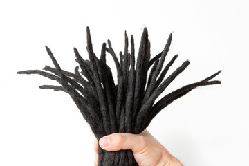 dreadlocks in hand, woven artificial kanekalon, for weaving into a hairstyle, close-up on a white...