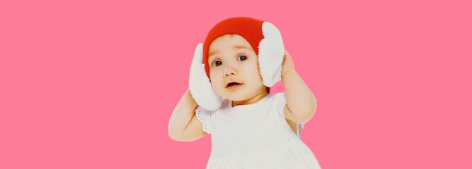 Portrait of little baby wearing winter knitted hat on pink background