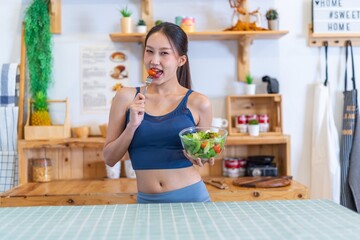 Young beautiful asian female adult lady in gym outfit after yoga exercise. Eat clean food salad with tomato for healthy and slim fit lifestyle.